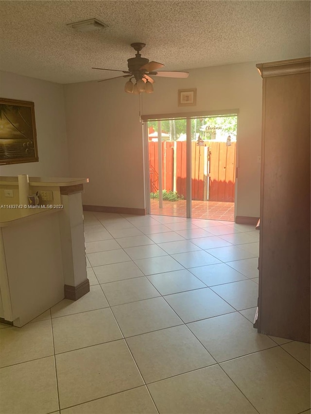 empty room featuring light tile floors, ceiling fan, and a textured ceiling