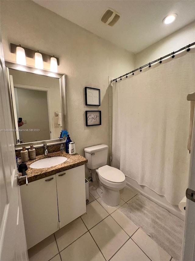 bathroom with toilet, vanity with extensive cabinet space, and tile flooring