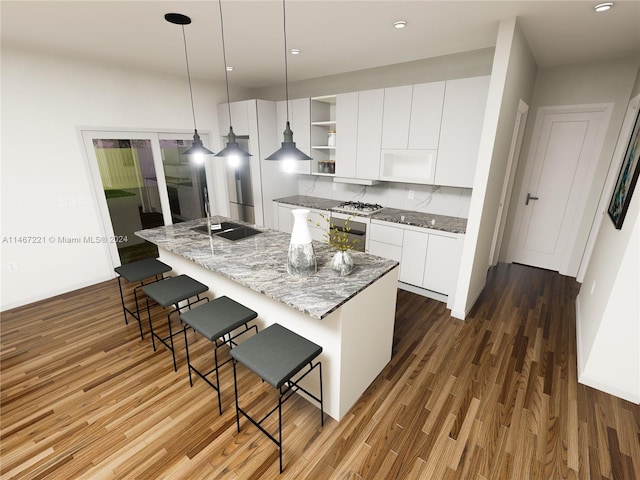 kitchen with white cabinetry, light stone countertops, decorative light fixtures, a center island with sink, and hardwood / wood-style floors