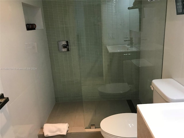 bathroom with a shower with shower door, vanity, tile patterned flooring, and toilet