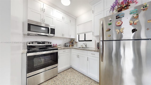 kitchen featuring white cabinetry, appliances with stainless steel finishes, sink, and light stone counters