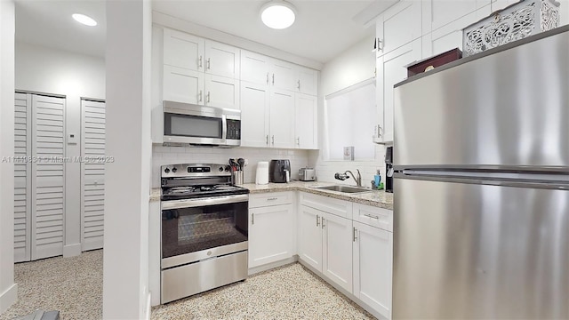 kitchen with white cabinets, appliances with stainless steel finishes, sink, and tasteful backsplash