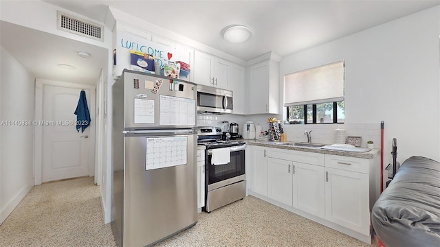 kitchen featuring appliances with stainless steel finishes, sink, white cabinets, and backsplash