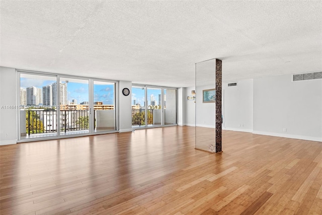 spare room with floor to ceiling windows, light hardwood / wood-style flooring, and a wealth of natural light