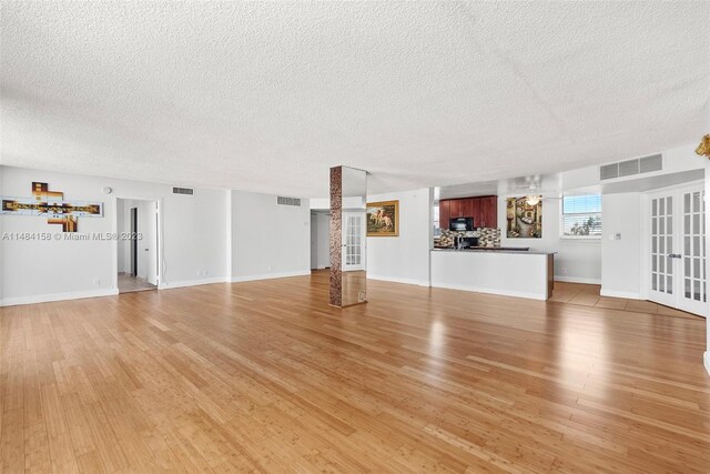 unfurnished living room with french doors, wood-type flooring, and a textured ceiling