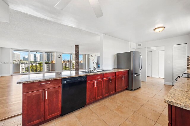 kitchen with light stone counters, ceiling fan, sink, stainless steel refrigerator, and black dishwasher