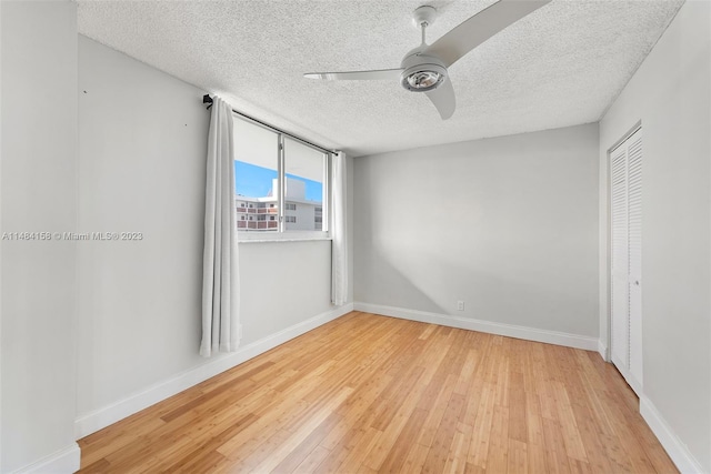 spare room with light hardwood / wood-style floors, ceiling fan, and a textured ceiling