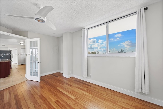 tiled empty room with french doors, ceiling fan, and a textured ceiling