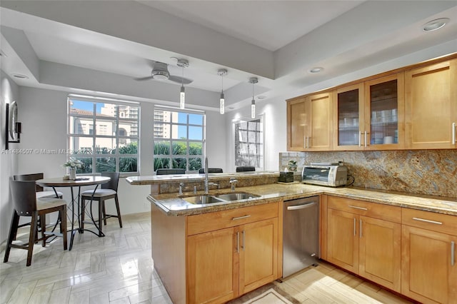 kitchen featuring kitchen peninsula, ceiling fan, hanging light fixtures, stainless steel dishwasher, and a tray ceiling