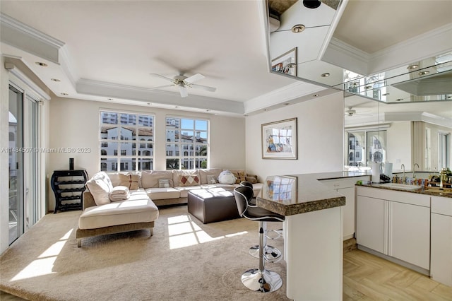 living room featuring light parquet floors, a tray ceiling, ceiling fan, and sink