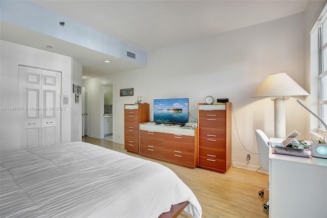 bedroom with light hardwood / wood-style floors and a closet