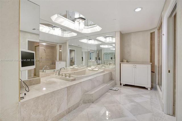 bathroom featuring tiled bath, vanity, and tile flooring