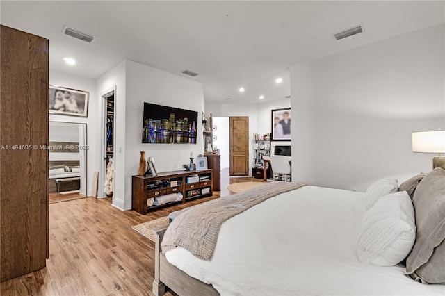 bedroom with a closet, a walk in closet, and light hardwood / wood-style flooring