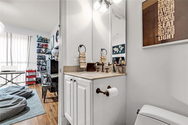 bathroom with toilet, wood-type flooring, and vanity