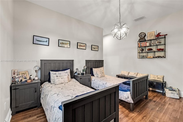 bedroom with dark hardwood / wood-style floors and an inviting chandelier