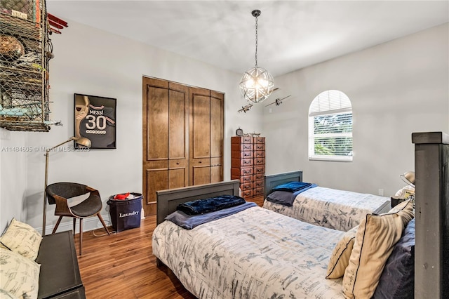 bedroom with a closet, a notable chandelier, and dark hardwood / wood-style floors