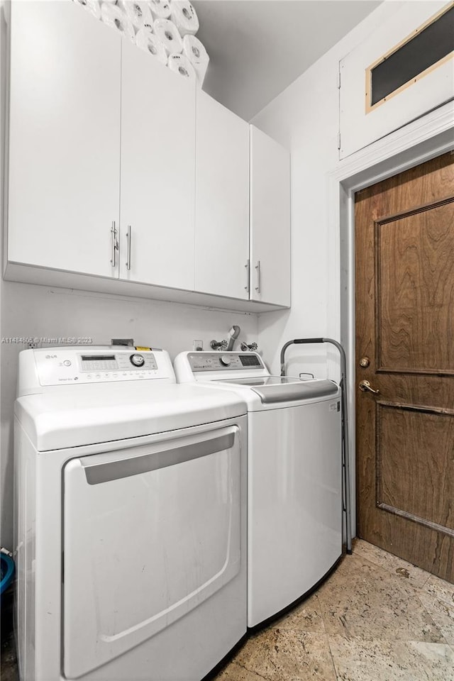 laundry area featuring cabinets, washing machine and clothes dryer, and light tile flooring