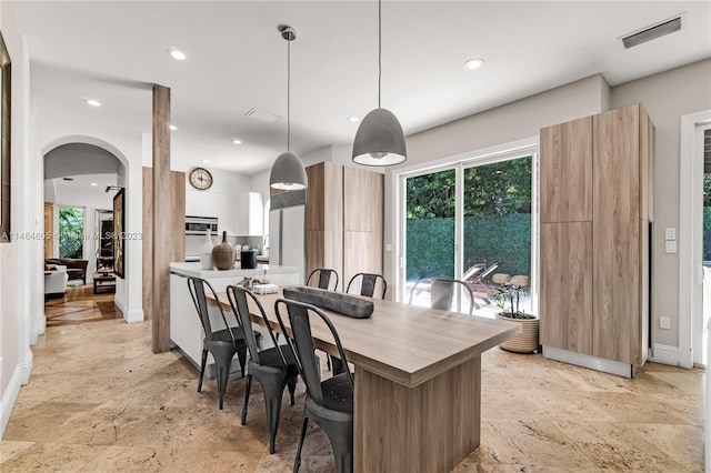 kitchen with light tile floors, a kitchen bar, and decorative light fixtures