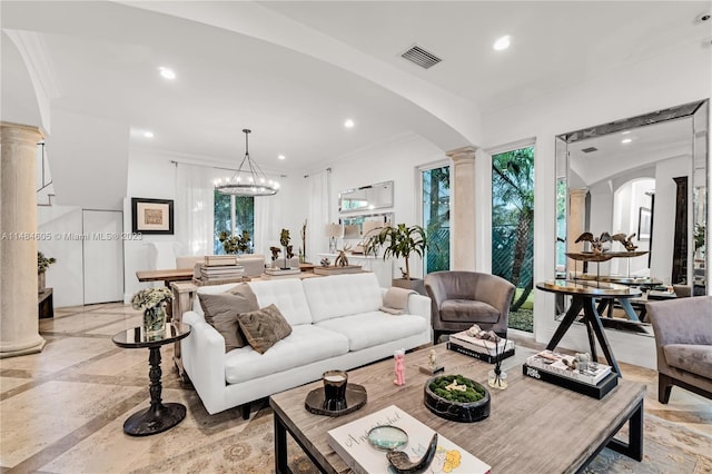 tiled living room with a notable chandelier, crown molding, and ornate columns