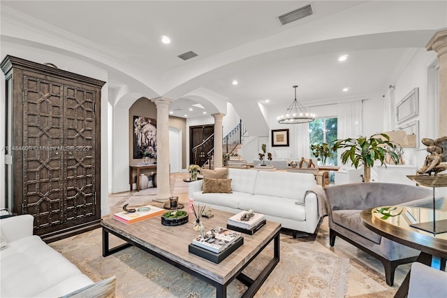 living room with crown molding, decorative columns, and a notable chandelier