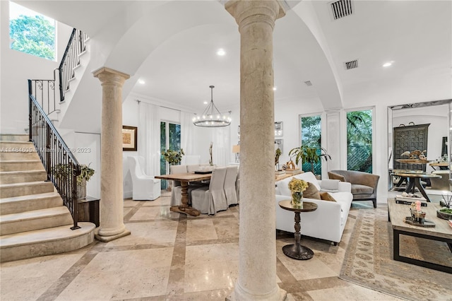 living room featuring crown molding, an inviting chandelier, light tile floors, and ornate columns