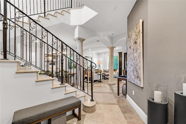 foyer entrance featuring decorative columns and light tile floors