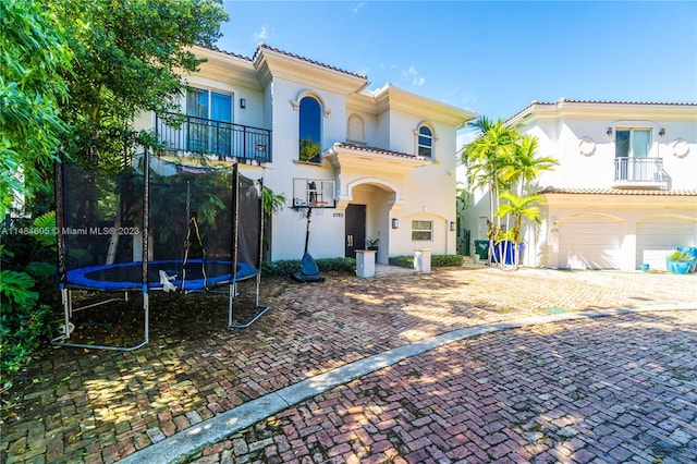 mediterranean / spanish-style house featuring a balcony, a trampoline, and a garage