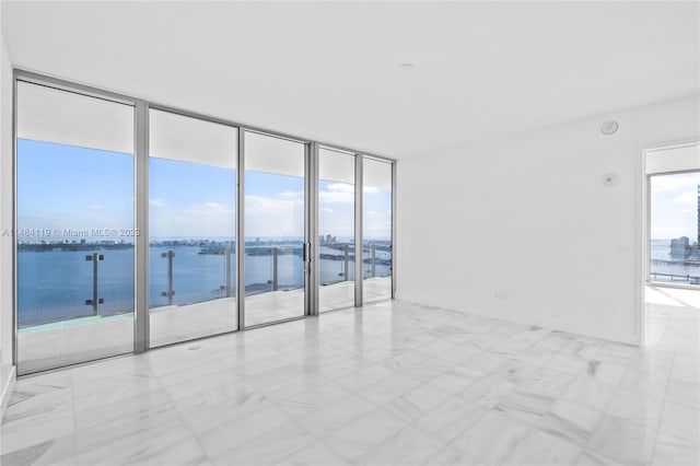 empty room featuring a water view, a wall of windows, and plenty of natural light