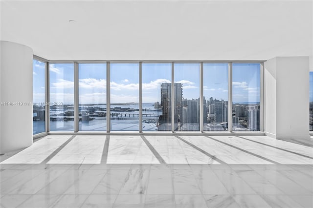 spare room featuring floor to ceiling windows and a water view