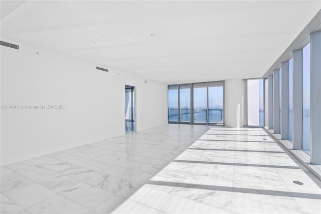 spare room featuring a wall of windows and a water view