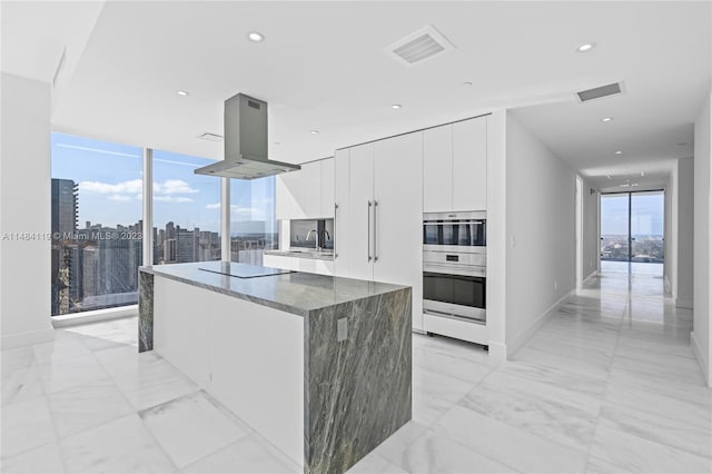 kitchen with island range hood, double oven, a kitchen island, black electric stovetop, and white cabinets