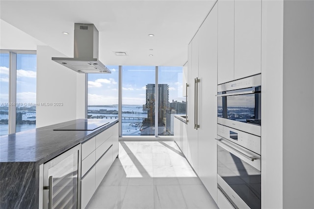 kitchen with white cabinetry, beverage cooler, expansive windows, and island exhaust hood