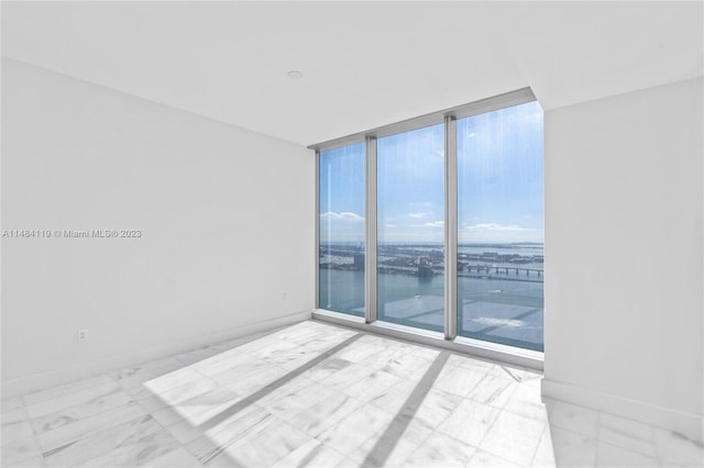 unfurnished room with plenty of natural light, expansive windows, and a water view