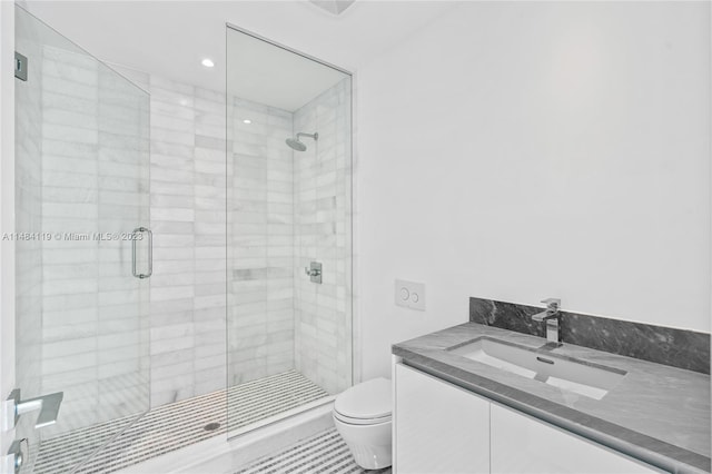 bathroom featuring a shower with door, vanity, and toilet