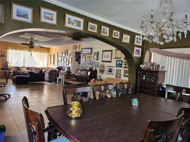 tiled dining area with ceiling fan with notable chandelier and ornamental molding