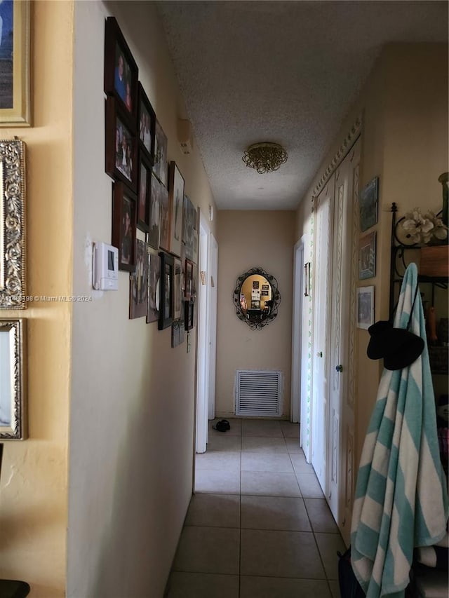 corridor featuring a textured ceiling and light tile patterned flooring