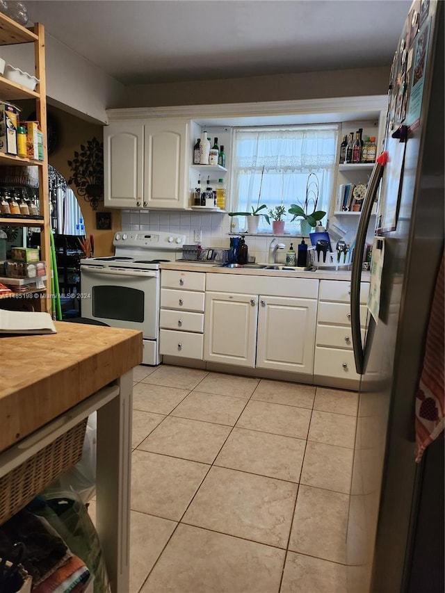 kitchen featuring light tile patterned floors, white cabinetry, sink, white electric range, and stainless steel fridge