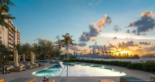 pool at dusk featuring a patio area