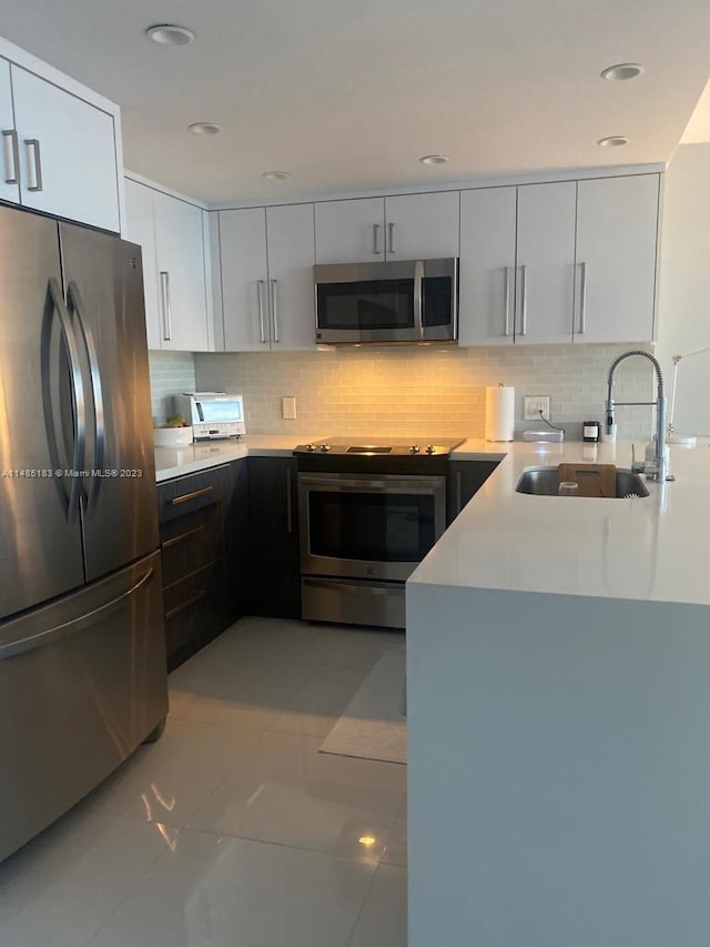 kitchen featuring sink, light tile floors, stainless steel appliances, tasteful backsplash, and white cabinetry