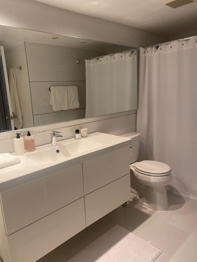 bathroom with tile flooring, vanity with extensive cabinet space, and toilet