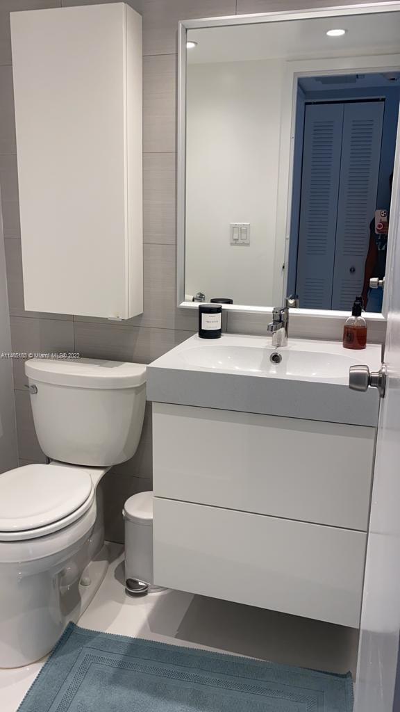 bathroom with vanity, toilet, and tile walls