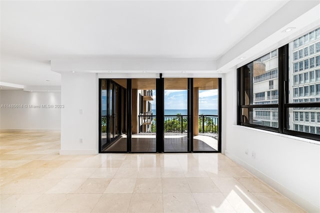 spare room featuring light tile floors and a water view