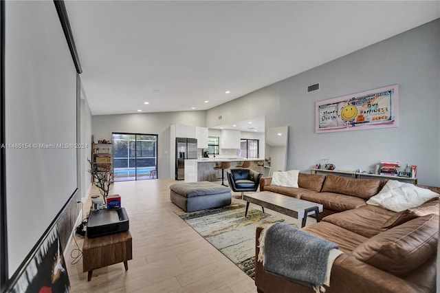 living room featuring lofted ceiling and light hardwood / wood-style floors