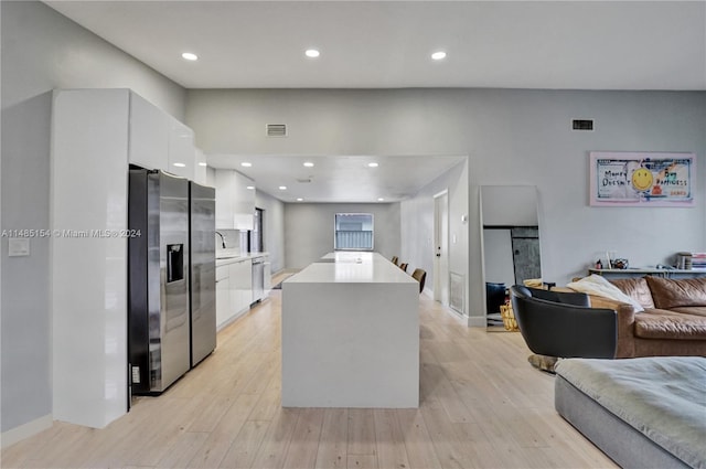 kitchen featuring white cabinets, stainless steel fridge with ice dispenser, light hardwood / wood-style flooring, and a center island