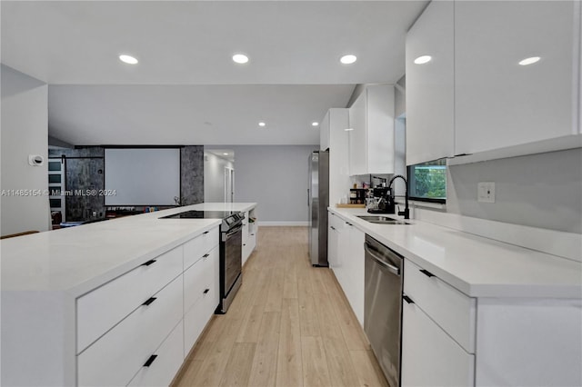 kitchen featuring light wood-type flooring, a kitchen island, stainless steel appliances, sink, and white cabinets