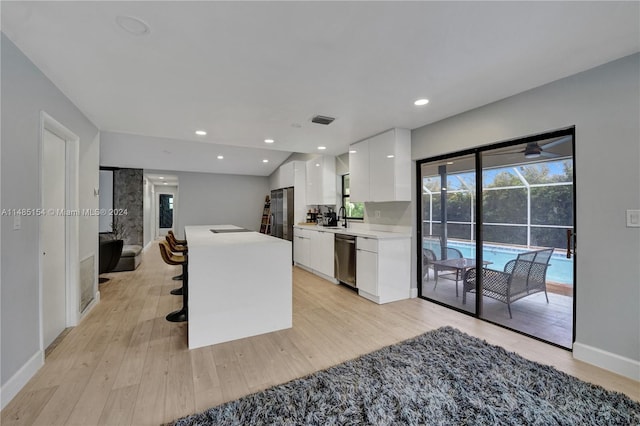 kitchen with white cabinets, dishwasher, a breakfast bar, and light wood-type flooring