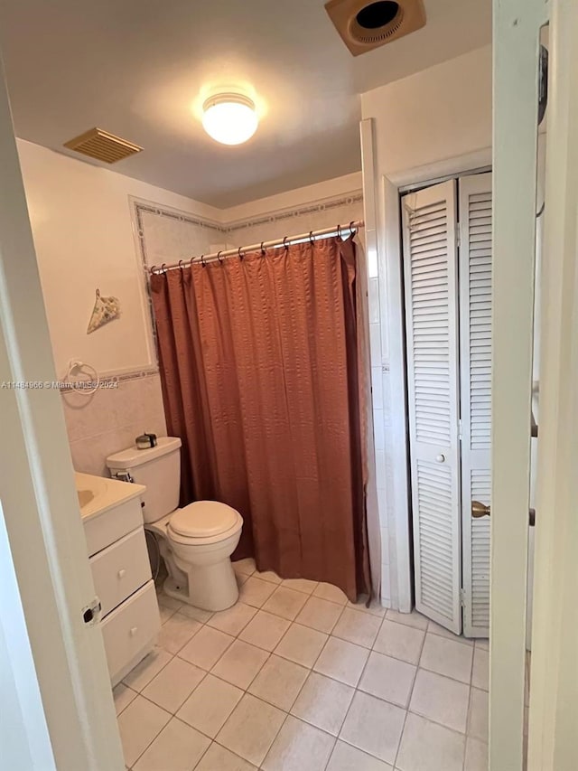 bathroom with vanity, toilet, tile walls, and tile patterned flooring