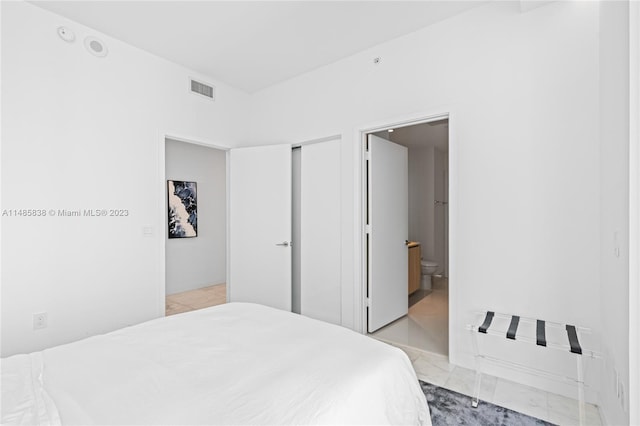 bedroom featuring ensuite bathroom and light tile floors