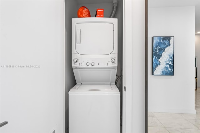 laundry area with stacked washer / drying machine and light tile floors