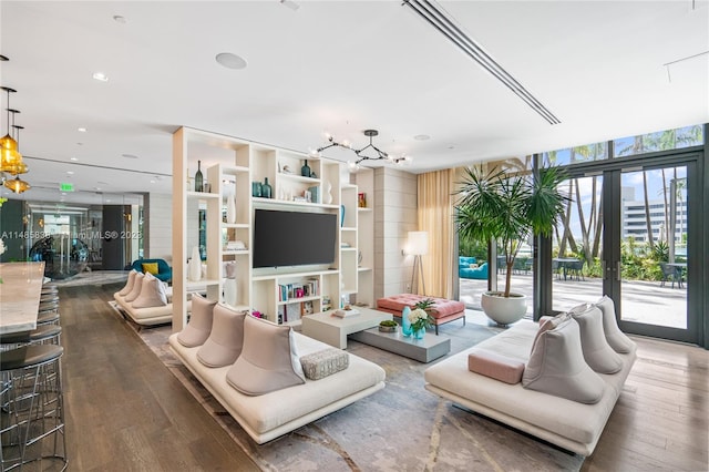 living room with a notable chandelier, dark hardwood / wood-style floors, and french doors